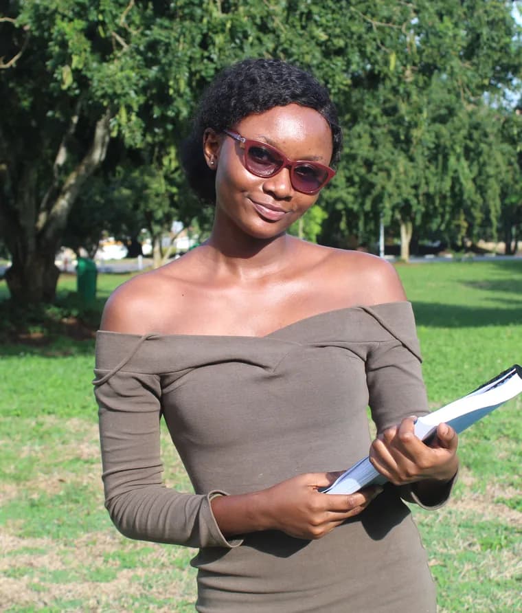 Graduate holding coursework in a park